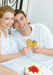 Young couple celebrating with champagne at bedroom