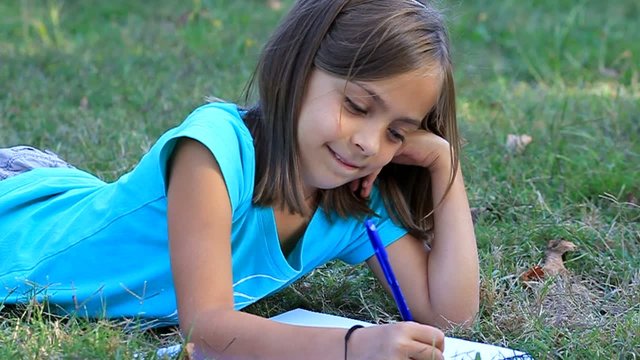 sourire en &eacute;crivant dans l'herbe