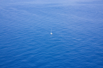 Single boat sailing in a vast ocean