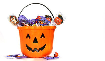 Jack-o-Lantern bucket filled with candies on white - Powered by Adobe