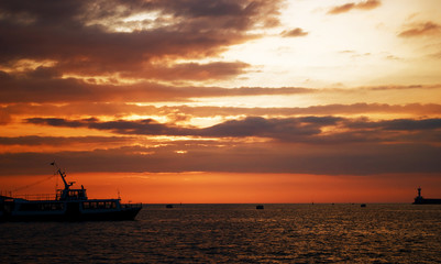 Yacht on horizon with golden orange clouds