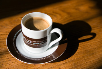 Cup of espresso on a wooden table in morning light