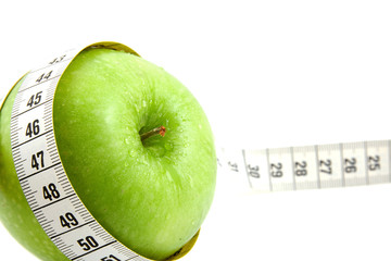 fresh green apple with measure tape over white background