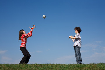 Kids playing ball outdoor against blue sky