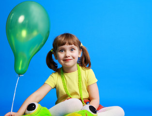 llittle girl holding colorful balloons on a blue background