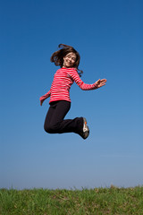 Girl jumping, running against blue sky