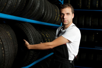 Fototapeta na wymiar Young mechanic choosing tire in tire store