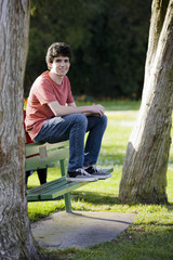 Naklejka premium Smiling Teenage Boy Sitting on Bench