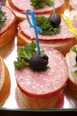 Open sandwiches with salami, olives and greens