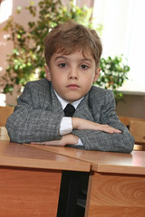 The pupil sits at a school desk