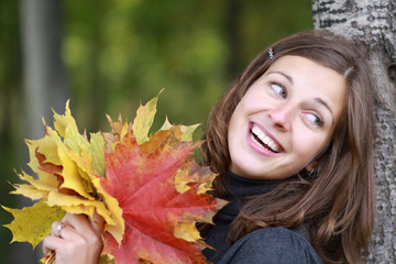 Beautiful romantic brunette with golden autumn leaf