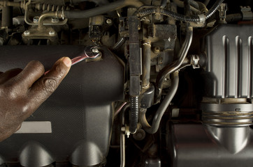 African or American mechanic hand and spanner servicing engine