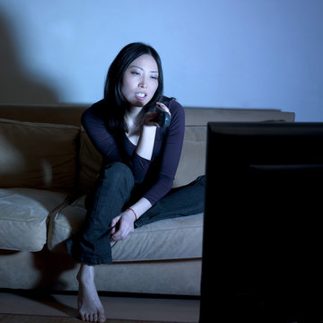 jeune femme asiatique t&eacute;l&eacute;commande t&eacute;l&eacute;vision
