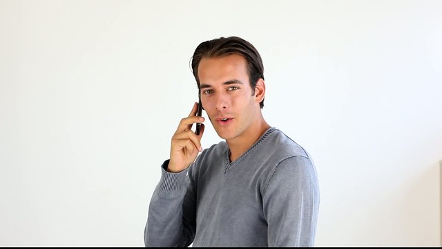 Jeune homme t&eacute;l&eacute;phonant, sur fond blanc