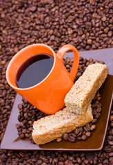 Cup of black coffee with beans and rusks
