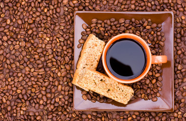 Naklejka premium Cup of black coffee with beans and rusks viewed from the top