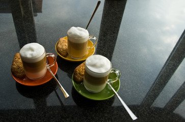 Three mugs with coffee and cream on dresser - 17338541