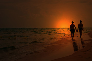 Fototapeta na wymiar love couple walking on the beach at sunset