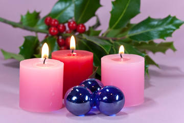 Obraz na płótnie Canvas Boże Narodzenie w świetle świec, liści ostrokrzewu i jagody