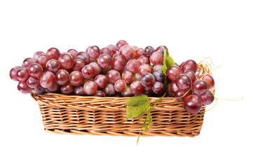Wooden basket and ripe grapes on a white.