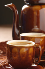 Cups of cappuccino and coffee pot