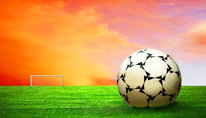 Soccer ball on green grass and sky background