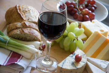 A glass of red wine and a selection of cheese