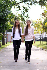 Obraz premium Fashionable girls twins walk in the street