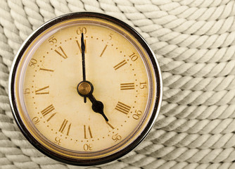 Clock with Roman numerals on cord background. 5