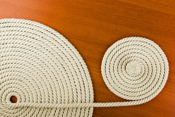 Heavy, white coiled rope on wooden background.
