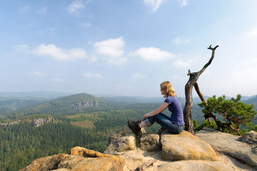 Frau sitzt auf Felsen im Elbsandsteingebirge