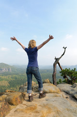 Frau steht auf Felsen im Elbsandsteingebirge und jubelt