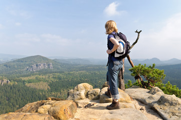 Frau mit Rucksack steht auf Felsen im Elbsandsteingebirge