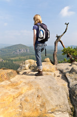 Frau mit Rucksack steht auf Felsen im Elbsandsteingebirge