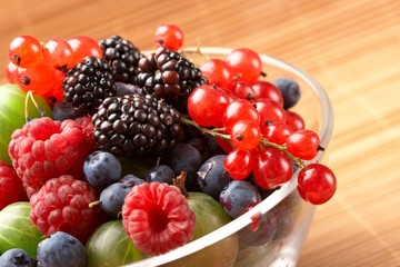 Fruit mix in the glass container, on a table from straw