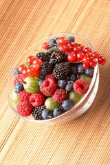Fruit mix in the glass container, on a table from straw