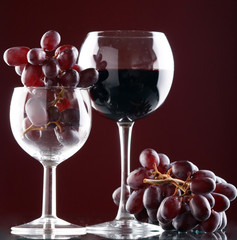 a glass of red wine and grape