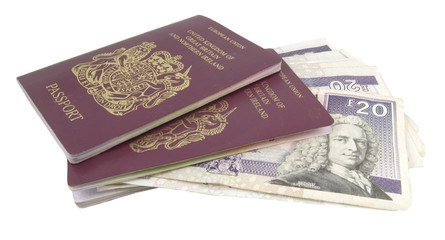 cash and two british passports on white background