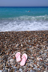 An image of flip-flops at the beach with pebble stones