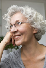 attraktive , lächelnde Seniorin mit Brille schaut nach oben
