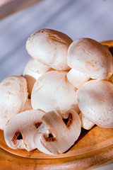 Group of white field mushroom on wood plate.