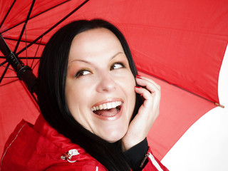 smiling brunette woman in fall, rainproof clothes holding umbrel