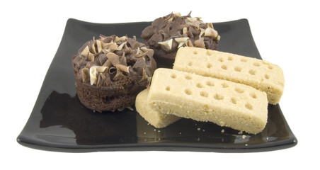 shortbread and fancy cake on black plate isolated on white