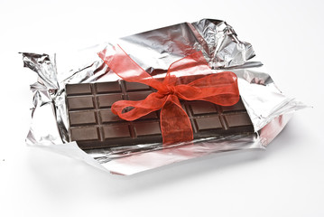 Black chocolate on a foil with red ribbon and bow