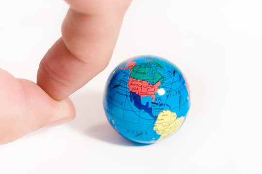 Human fingers ready to push a small globe