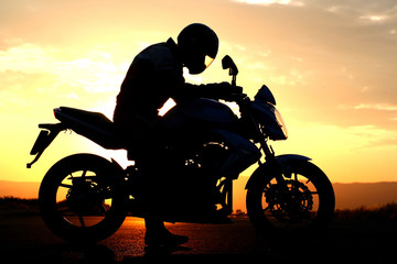 Naklejka na ściany i meble Sylwetka motocyklista na zachodzie słońca