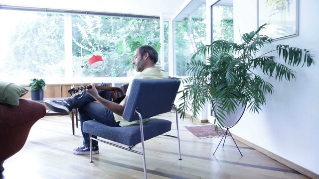mann spielt guitarre im wohnzimmer
