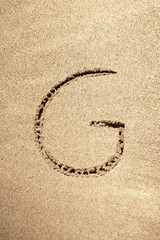 Alphabet letter G handwritten in sand