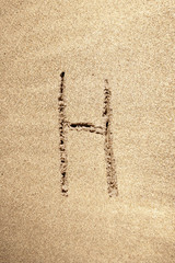 Alphabet letter H handwritten in sand