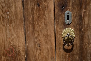An old wooden door with inlaid door-knocker and lock